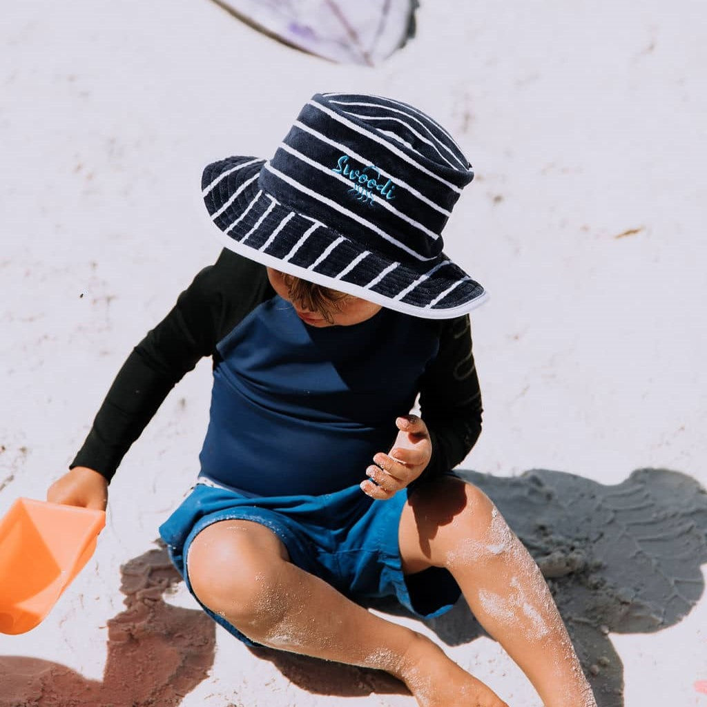 Young boy wearing UPF 50+ sun protection hat, while playing on the beach with toys in Esperance.