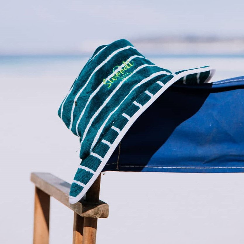 Turquoise with green Swoodi UPF 50+ sun protection hat, positioned on beach chair at Esperance beach
