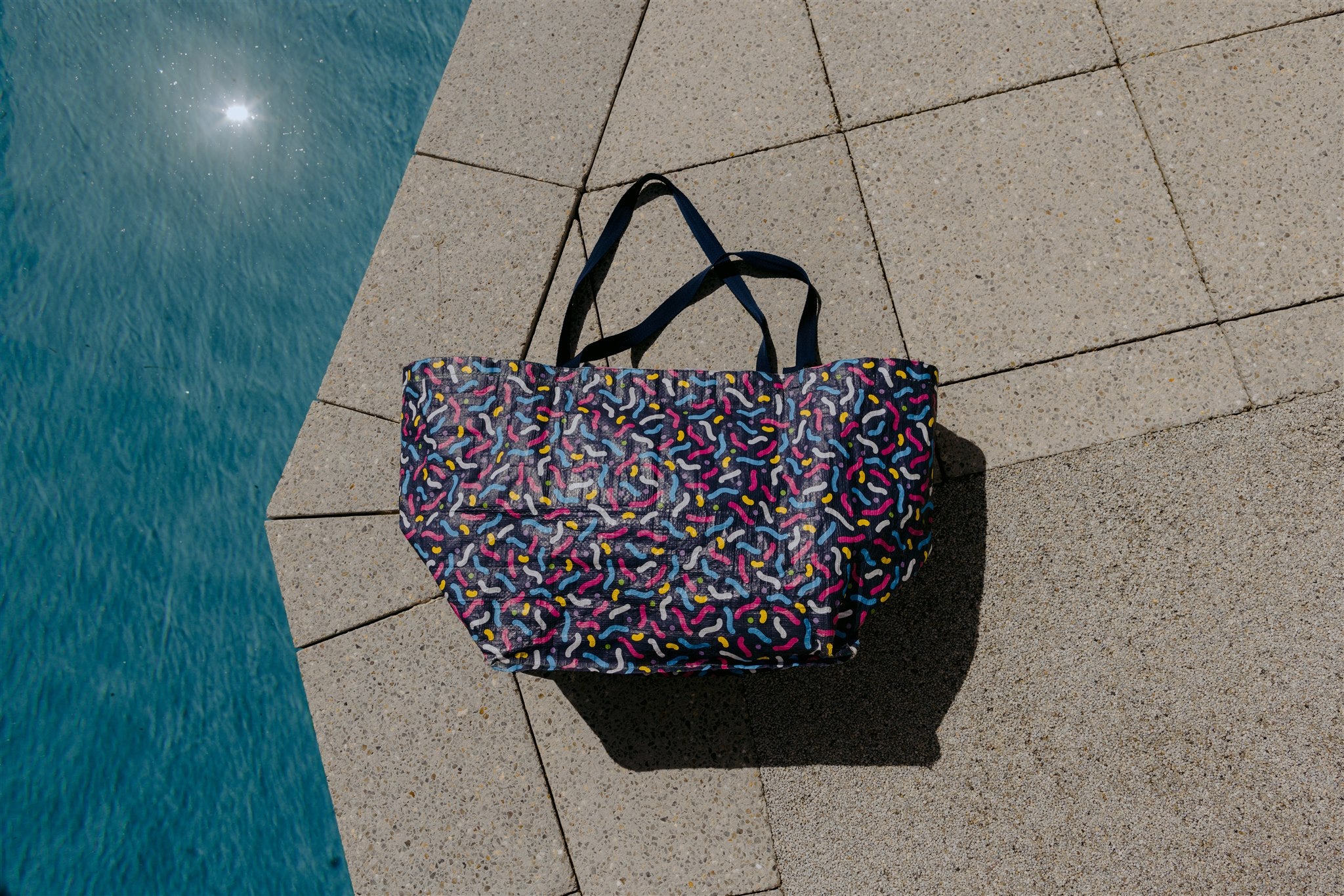 Flat lay by the pool of water proof beach bag with custom print