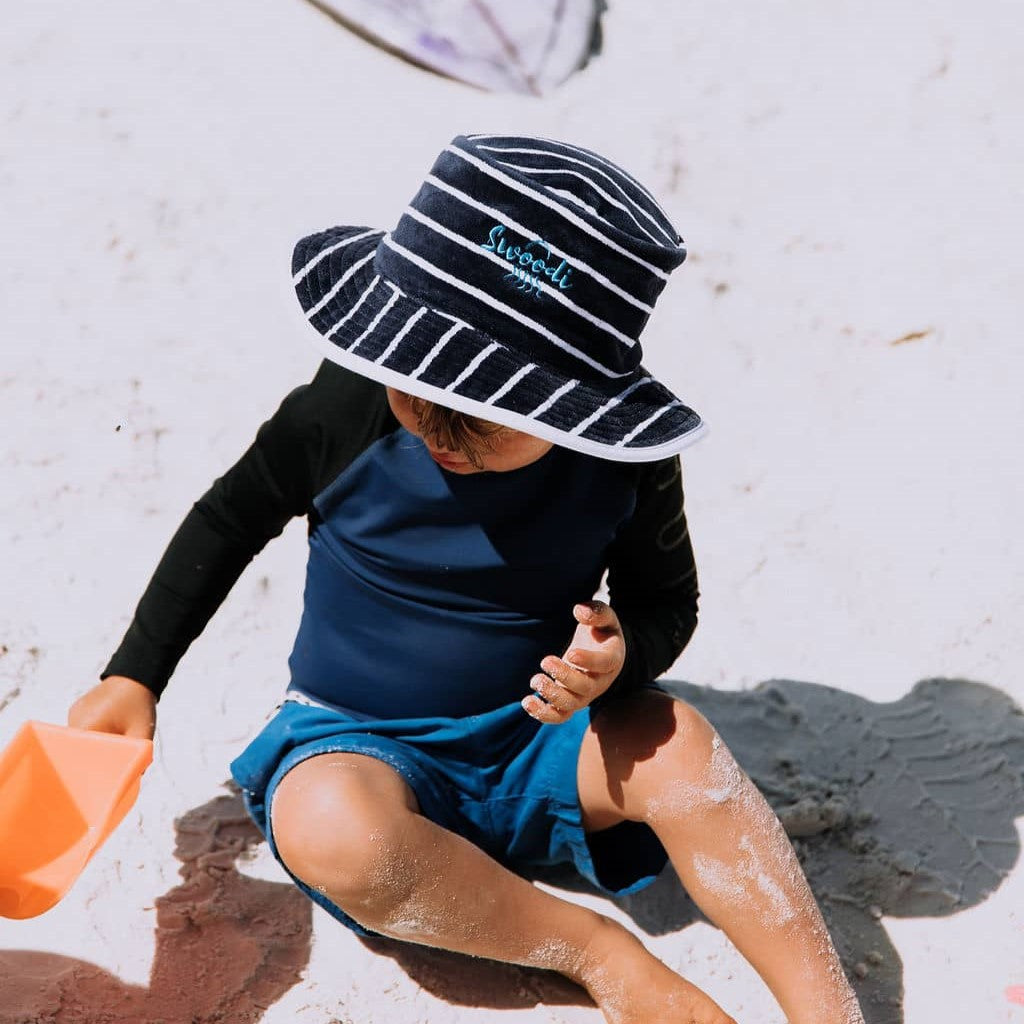 Young boy wearing UPF 50+ sun protection hat, while playing on the beach with toys in Esperance. 