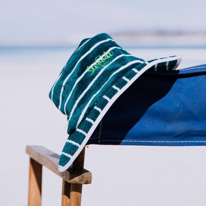 Turquoise with green Swoodi UPF 50+ sun protection hat, positioned on beach chair at Esperance beach 