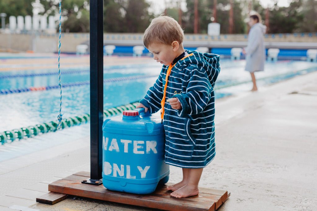 Toddler standing by pool in turquoise stripe swim hoodie