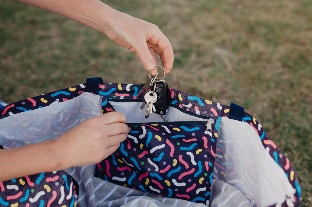 Putting keys in to zip up pocket on water proof beach bag