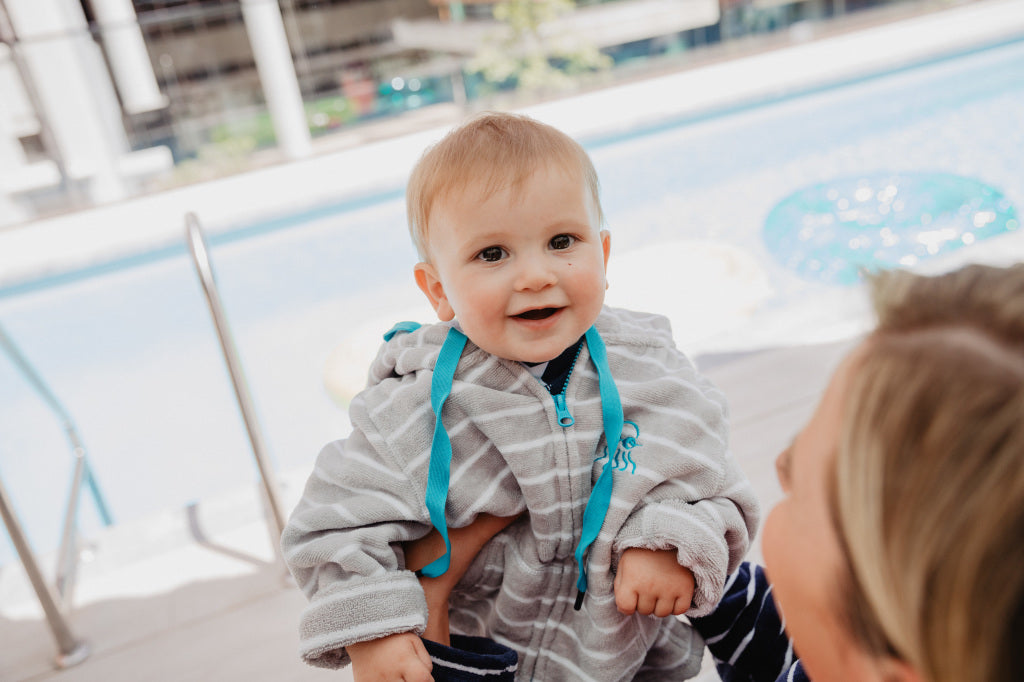 Baby wearing swim hoodie grey stripe with blue trim 