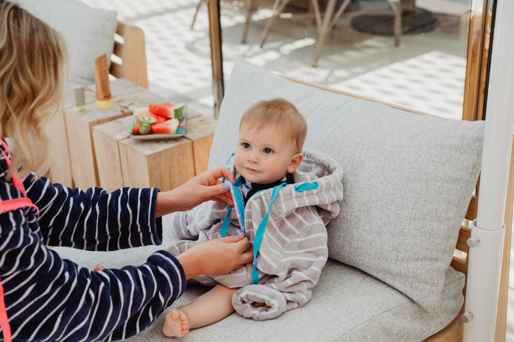 Mum zipping up babies zip up towel in grey stripe with blue trims 