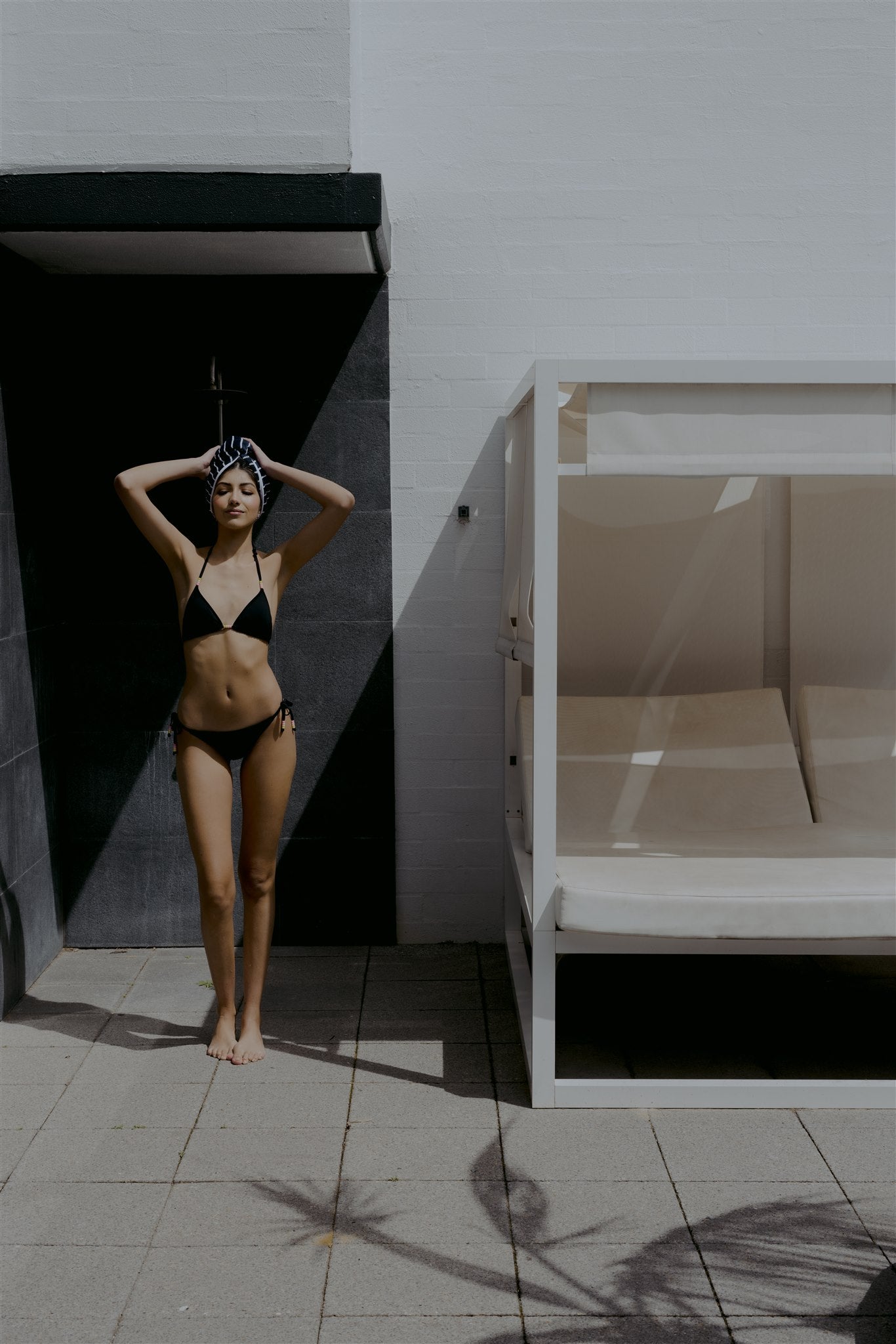 Female model in front of outdoor shower wearing bikini and navy and white stripe swoodi hair wrap 