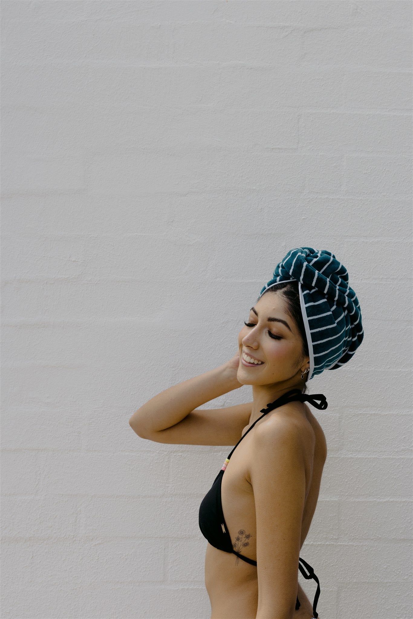 Side view of female model wearing bikini and turquoise hair wrap