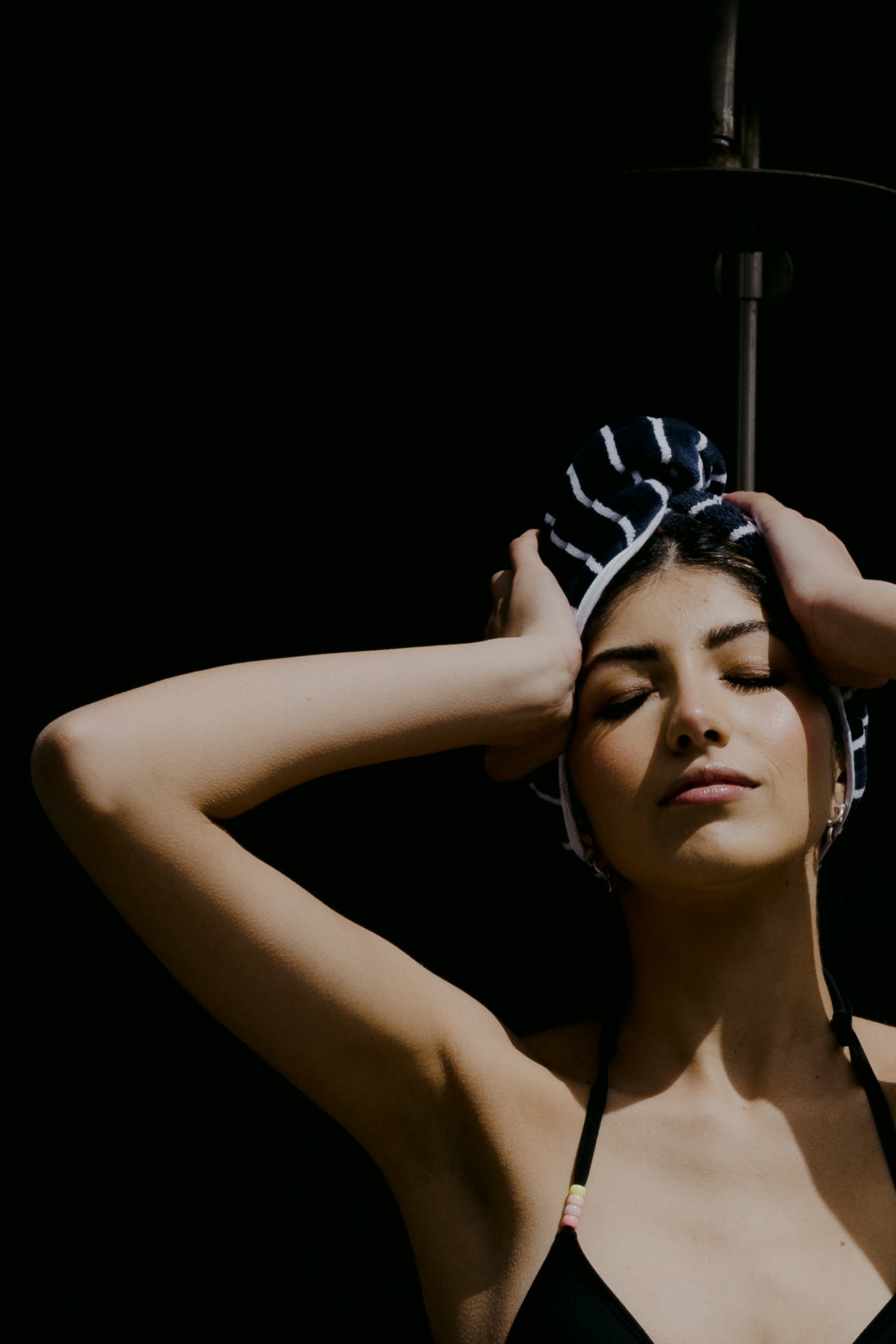 Female model in front of outdoor shower wearing swoodi hair wrap 