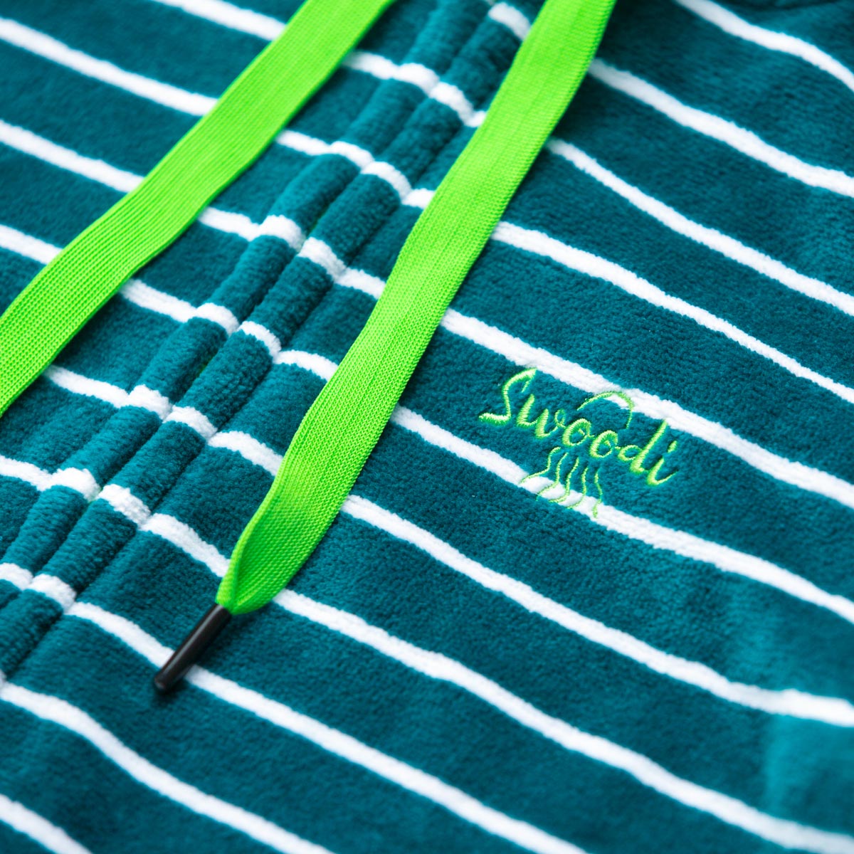 Close up of embroidery flat lay of turquoise swim hoodie with green strings 